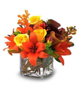 red lilies and yellow roses in glass cube vase