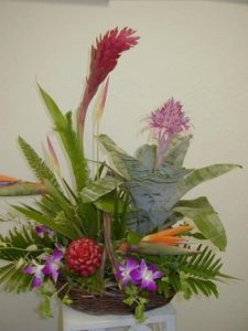 This unique design features a Bromeliad plant incorporated in it's own basket. Surrounded by fresh cut tropical flowers & orchids, it creates a most unique gift. 