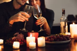 Couple drinking wine by candles and grapes